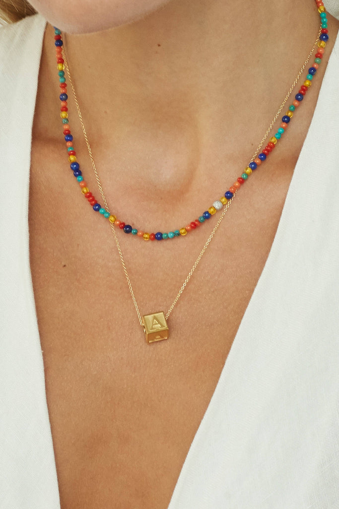 Cropped view on model 14K Diamond Multi-Bead Necklace layered with letter block Necklace bagatiba