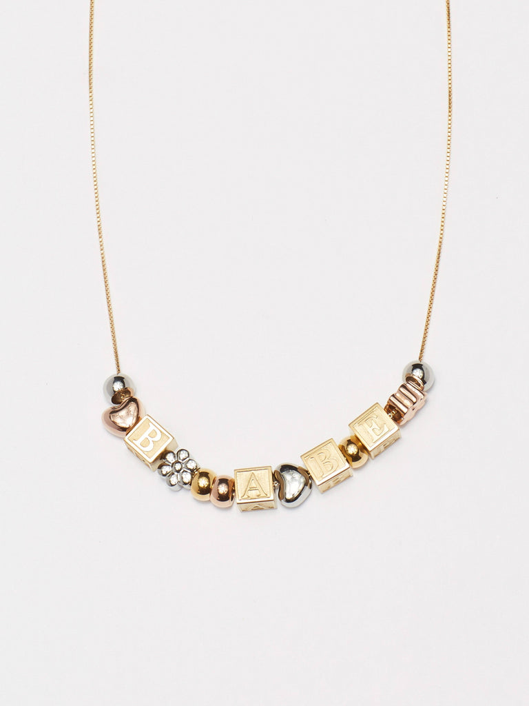Cropped flat lay view of Gold Bead Set mixed with Letter Blocks on chain  Bagatiba