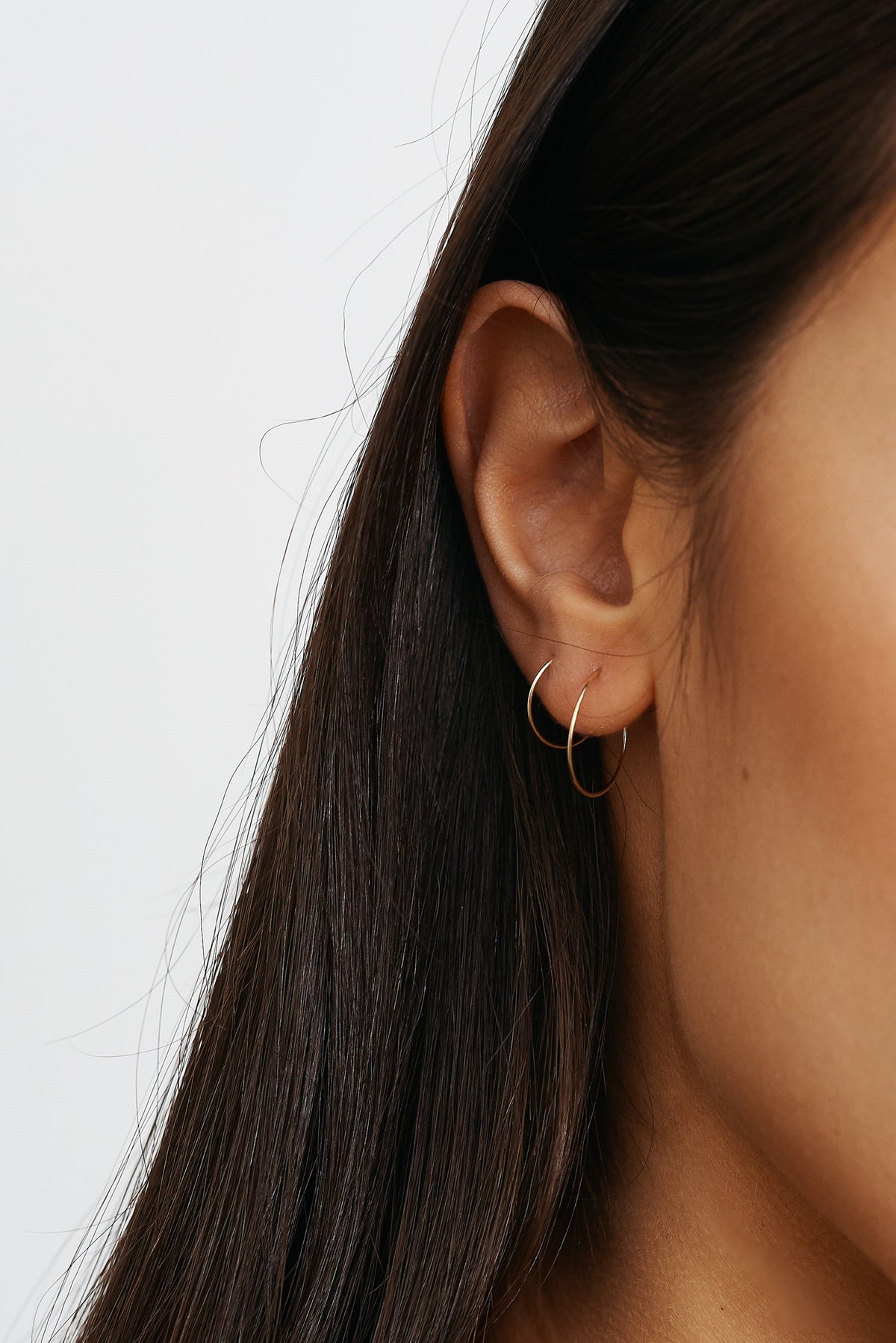 Cropped view of models ear 14K 301 Mini Hoops Earrings paired with size 302 Bagatiba 