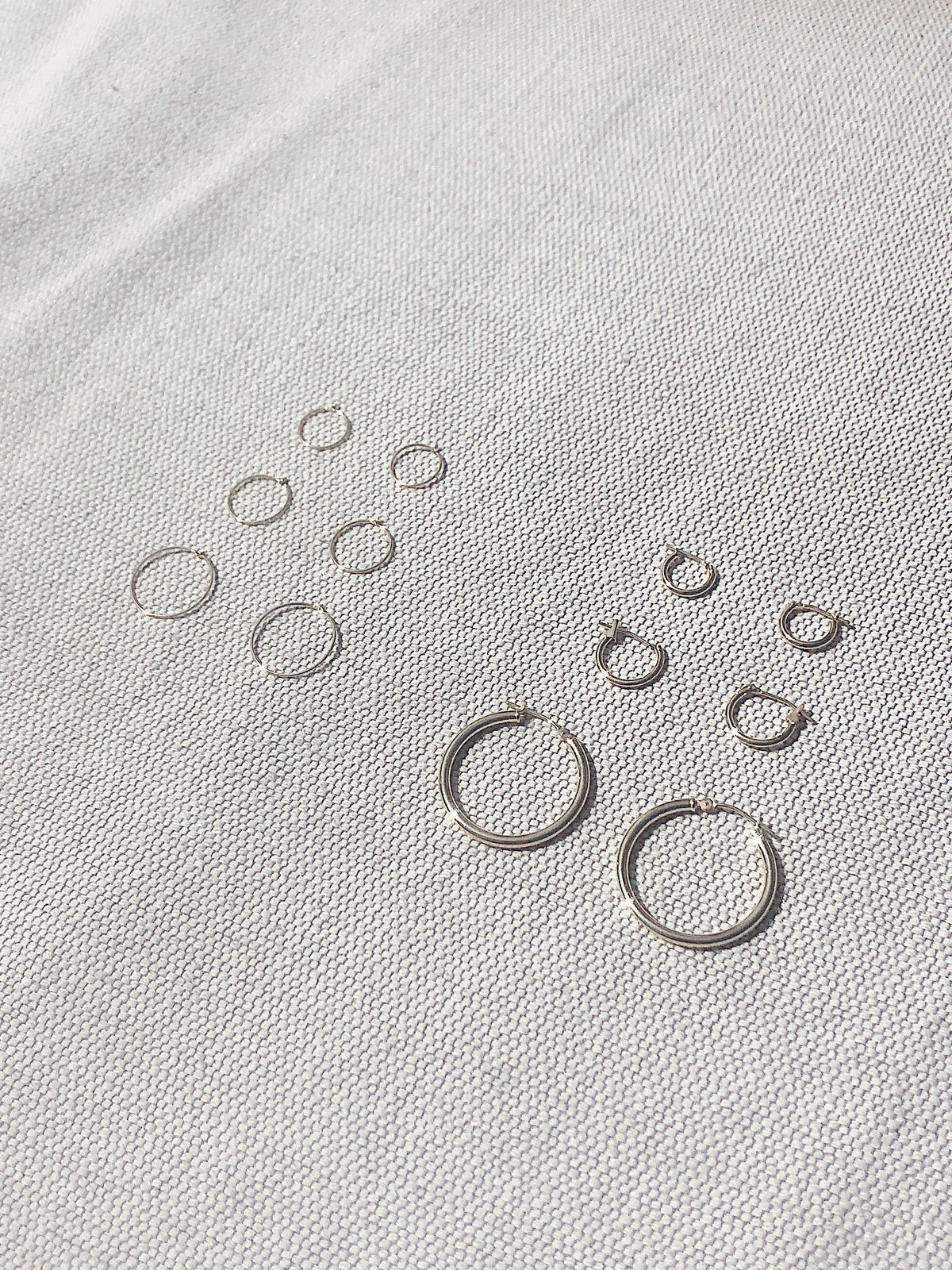 Full view flat lay of 14K 302 Mini Hoops Earrings with 1M, 2M, 3M, 14k 301, 303 hoops for size comparison Bagatiba