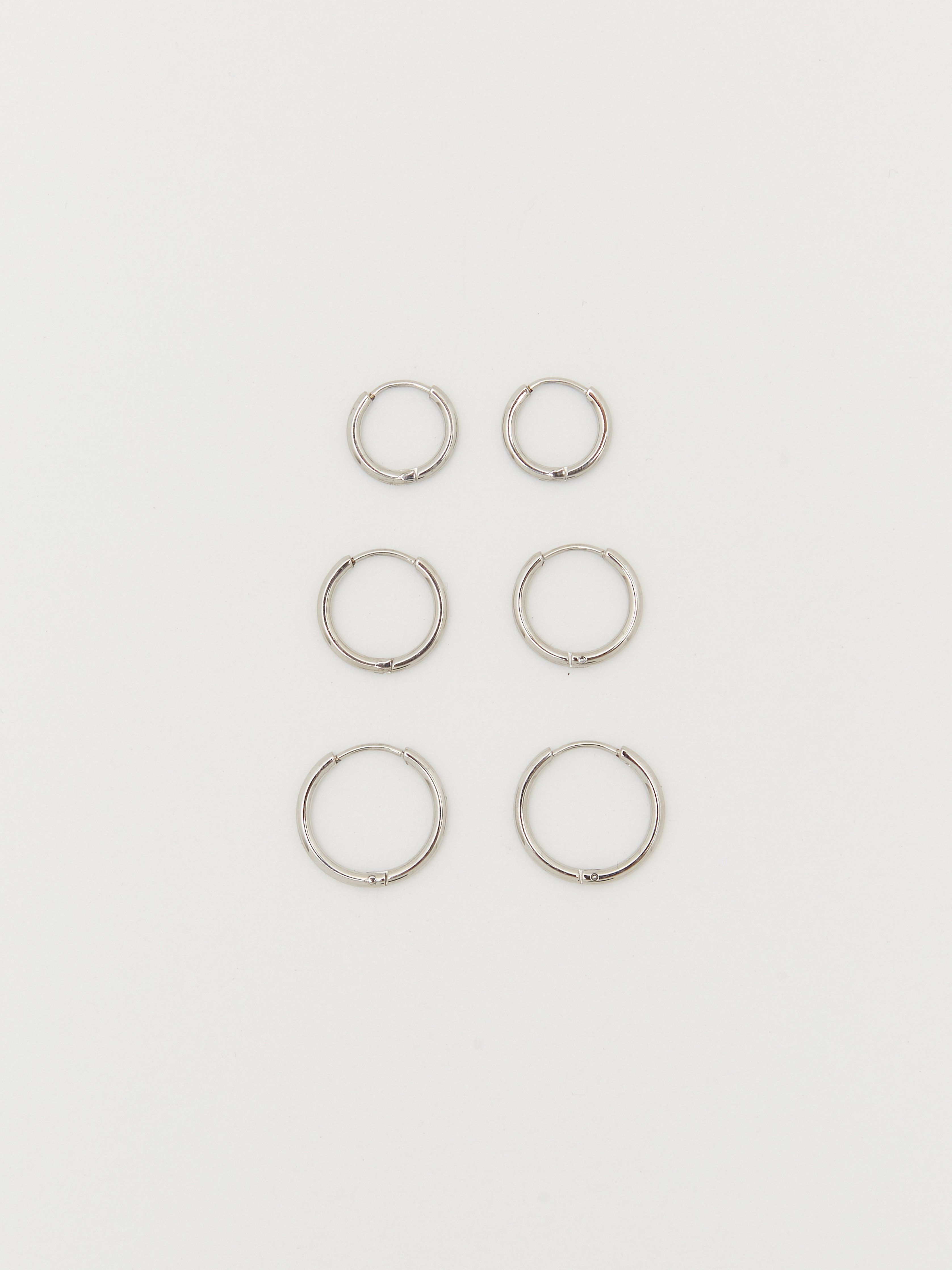 Flat lay view of Small, Medium and Large Silver Eco Huggies Earrings Bagatiba 